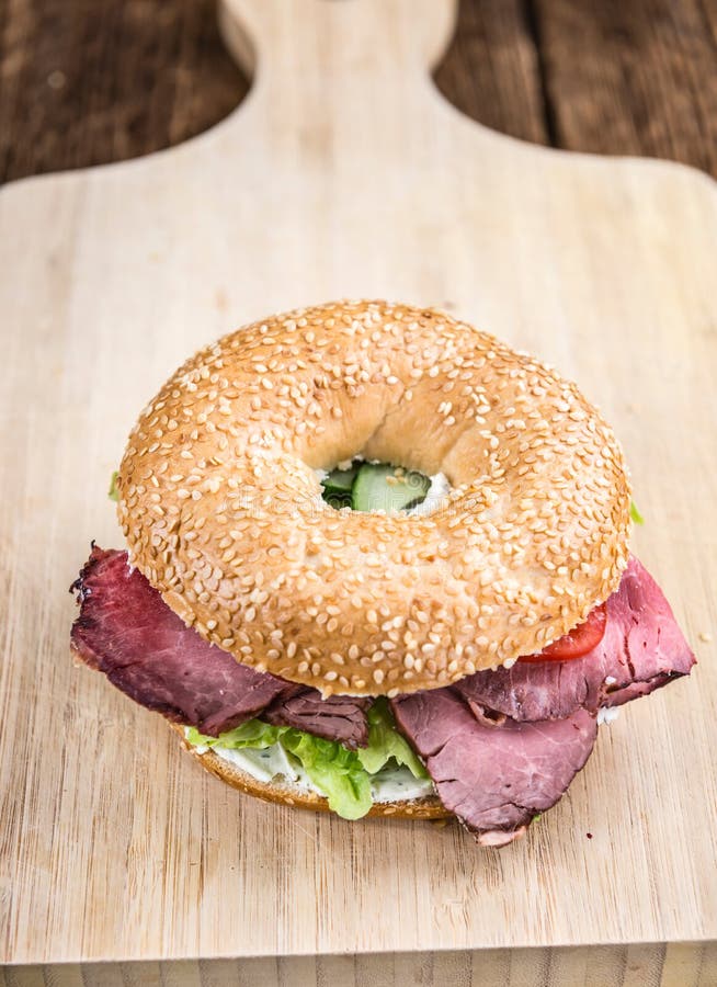 Bagel (mit Roastbeef) auf Weinlesehintergrund lizenzfreies stockbild Bagel (mit Roastbeef) auf Weinlesehintergrund lizenzfreies stockbild