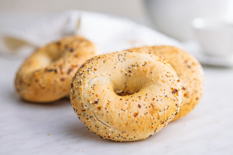 Bagel sprinkled with fried onion, sesame and poppy seeds on kitchen table stock photo