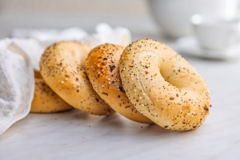 Bagel sprinkled with fried onion, sesame and poppy seeds on kitchen table royalty free stock photography