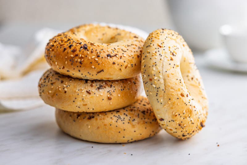 Bagel sprinkled with fried onion, sesame and poppy seeds on kitchen table royalty free stock images