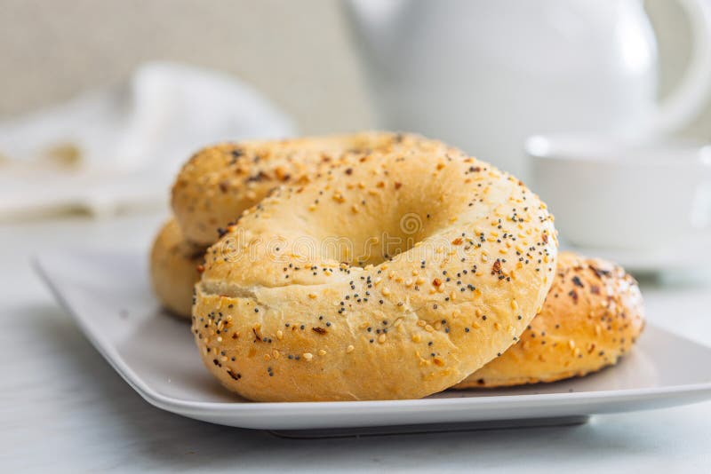 Bagel sprinkled with fried onion, sesame and poppy seeds on plate on kitchen table stock images