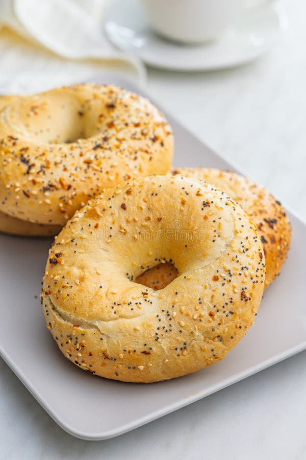 Bagel sprinkled with fried onion, sesame and poppy seeds on plate on kitchen table royalty free stock image