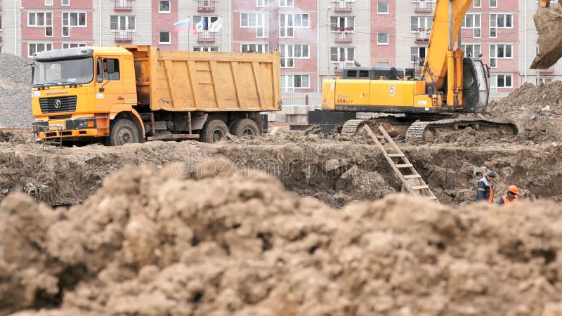 Bagger lädt Lehm unter Verwendung des Eimers in Kipplaster