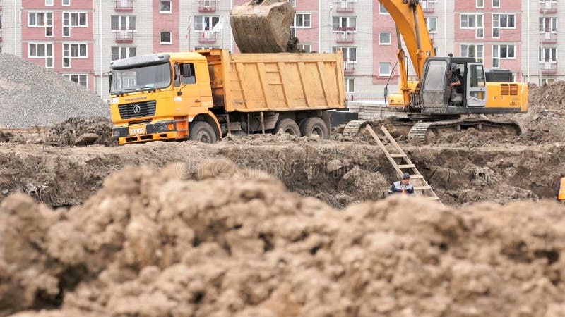 Bagger lädt Lehm unter Verwendung des Eimers in Kipplaster