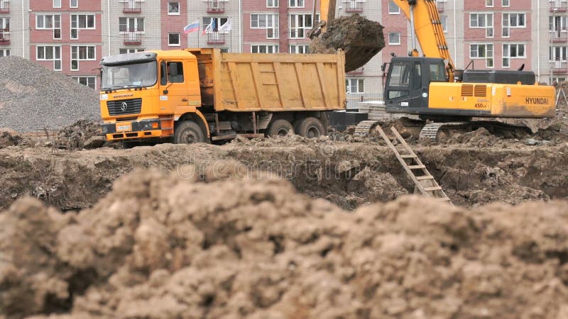 Bagger lädt Lehm unter Verwendung des Eimers in Kipplaster