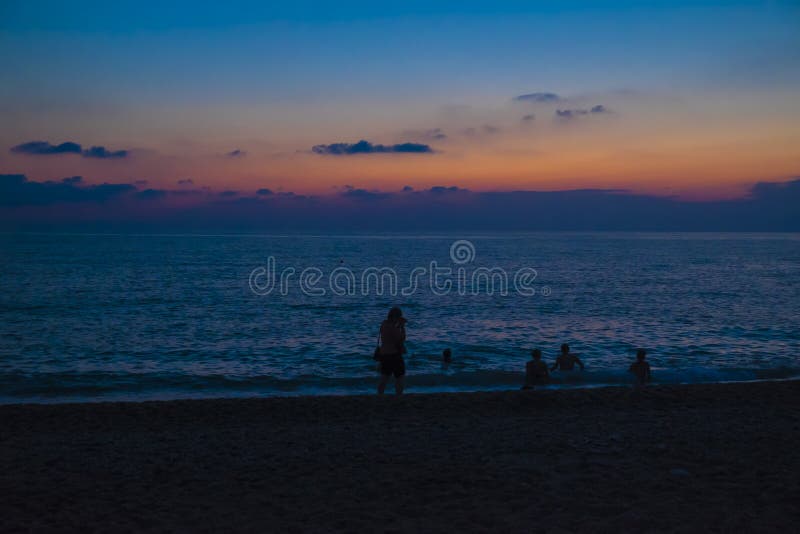 Bagnanti su una spiaggia del mare dopo il tramonto