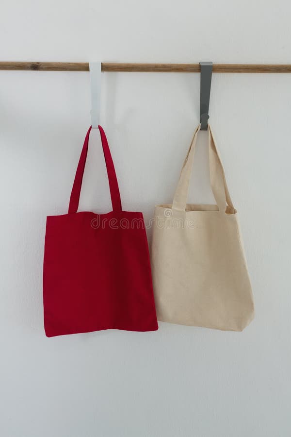 Bags hanging on hook against white wall