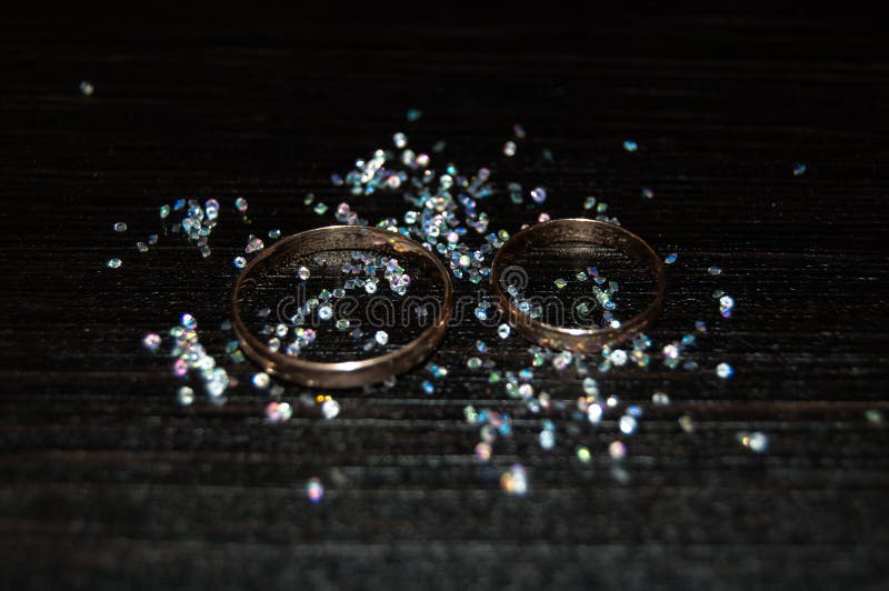 Wedding rings in a scattering of rhinestones on a dark background. Wedding rings in a scattering of rhinestones on a dark background