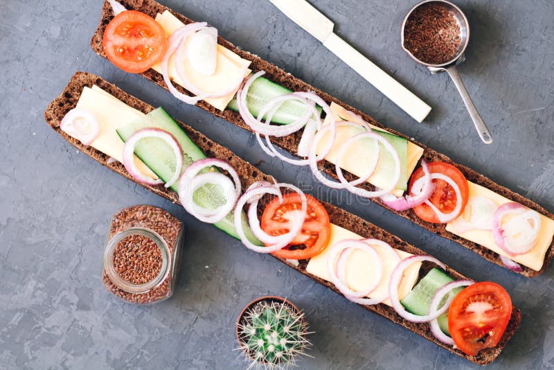 Baguette crujiente largo caliéntese, recientemente pan cocido centeno con queso, pepino y los tomates con las cebollas en un rúst fotos de archivo Baguette crujiente largo caliéntese, recientemente pan cocido centeno con queso, pepino y los tomates con las cebollas en un rúst fotos de archivo
