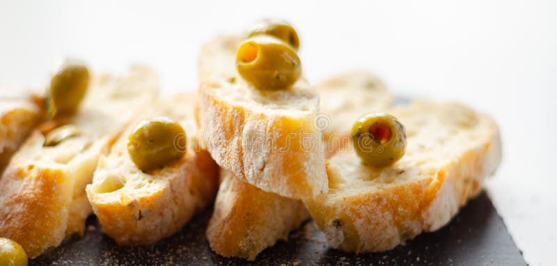 Baguette imbottita di olive tagliate con olive verdi fresche e prezzemolo servito su una piastra di pietra fotografia stock libera da diritti