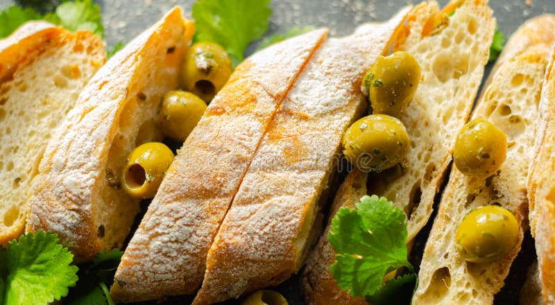 Baguette imbottite di olive, tagliate con olive verdi fresche e prezzemolo, servite su una piastra di pietra fotografia stock libera da diritti