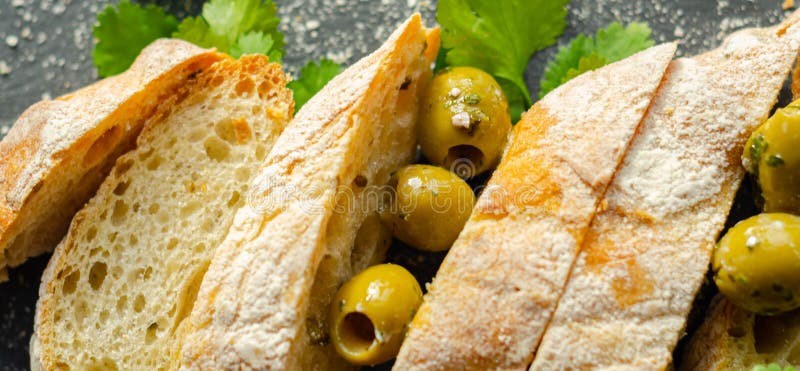 Baguette imbottite di olive, tagliate con olive verdi fresche e prezzemolo, servite su una piastra di pietra fotografia stock libera da diritti