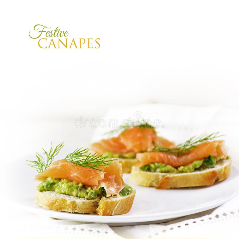 Baguette slices with smoked salmon and avocado cream or guacamole as a healthy party snack, background fades to white with sample