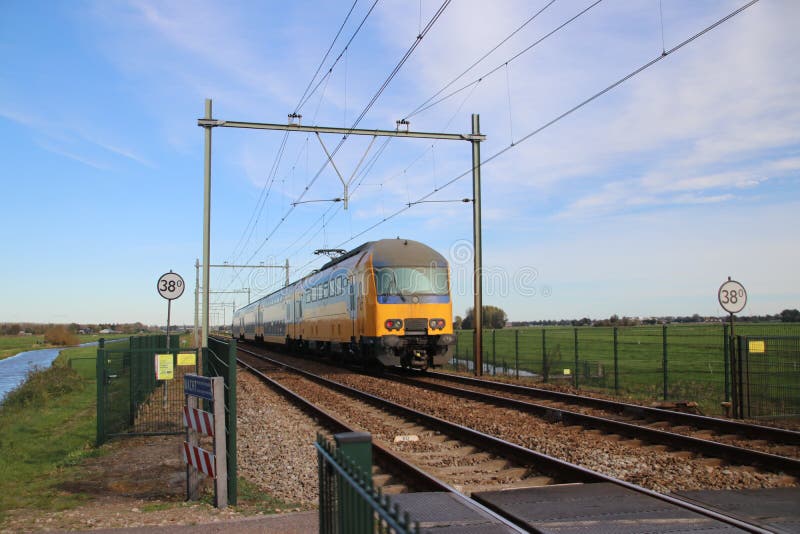 Bahnstrecke mit gelbem blauem niederländischem Doppeldeckerzug zwischen Gouda und Rotterdam bei Moordrecht stockfotos Bahnstrecke mit gelbem blauem niederländischem Doppeldeckerzug zwischen Gouda und Rotterdam bei Moordrecht stockfotos