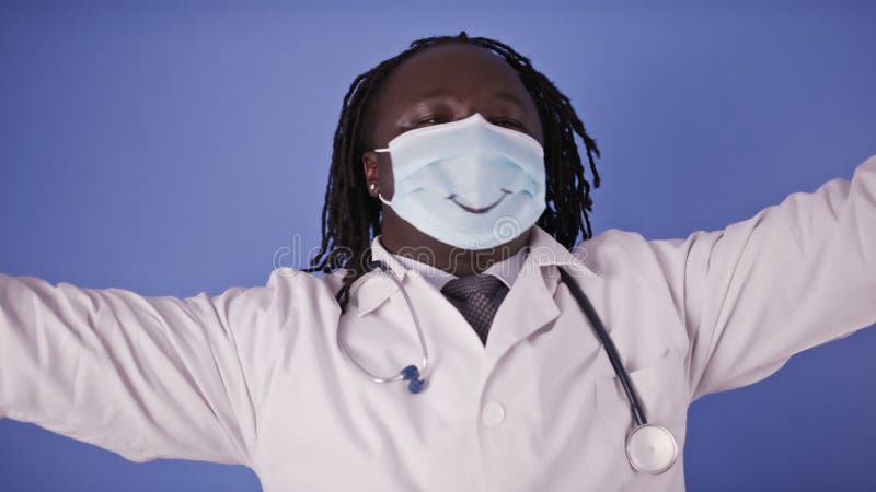 Bailando alegre y feliz doctor africano con máscara facial con dibujo de sonrisa metrajes