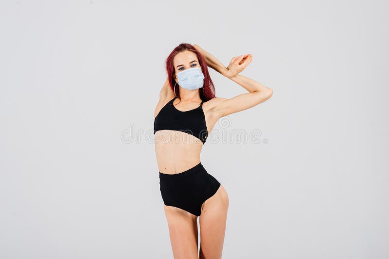 Female dancer in the styles of strip plastic and pole dance with face mask on light background. Female dancer in the styles of strip plastic and pole dance with face mask on light background