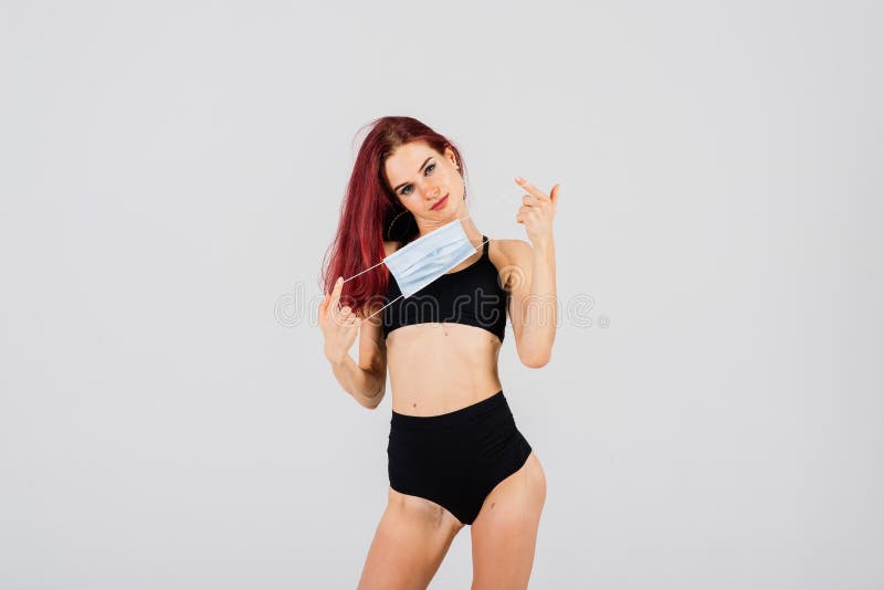 Female dancer in the styles of strip plastic and pole dance with face mask on light background. Female dancer in the styles of strip plastic and pole dance with face mask on light background