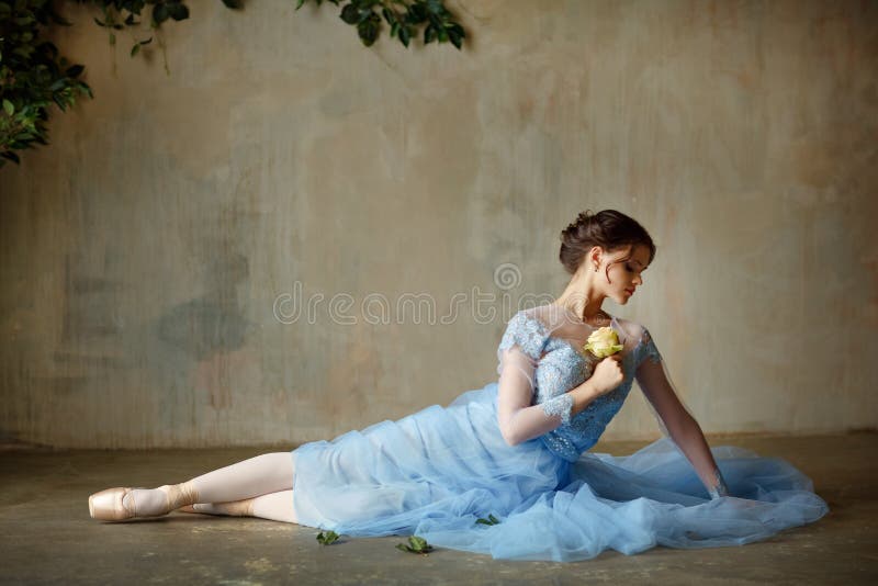 A bailarina graciosa bonita da menina em um vestido azul e o pointe sentam-se foto de stock royalty free A bailarina graciosa bonita da menina em um vestido azul e o pointe sentam-se foto de stock royalty free