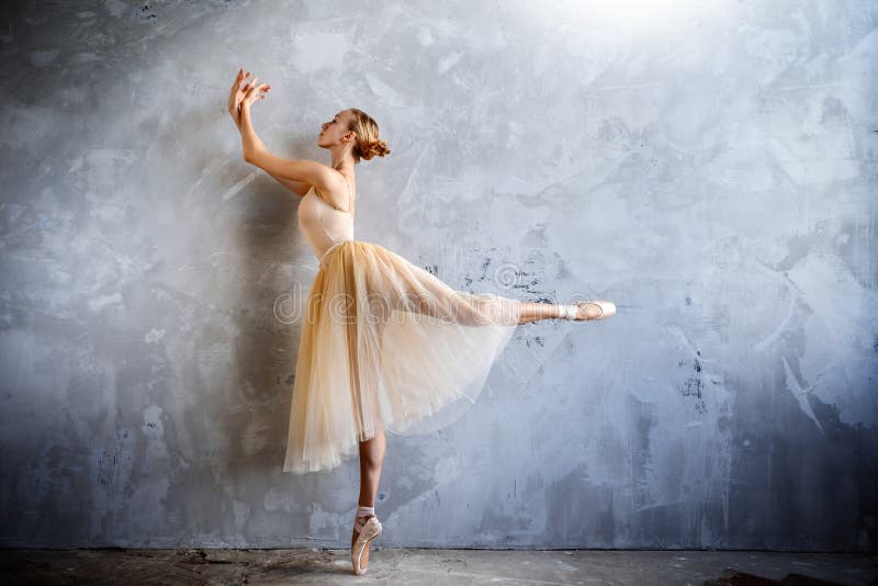 A bailarina nova em um traje de dança colorido dourado está levantando em um estúdio do sótão foto de stock A bailarina nova em um traje de dança colorido dourado está levantando em um estúdio do sótão foto de stock
