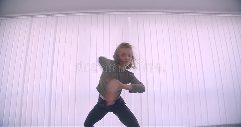Bailarina profesional cauc? sica blanda que baila activamente y que hace girar en estudio ligero en fondo de las lumbreras almacen de metraje de vídeo