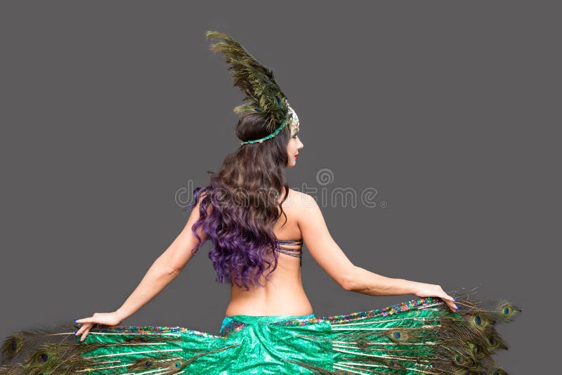 Mujer en traje de carnaval de plumas de pavo real sentada en el piso,  aislar fondo negro