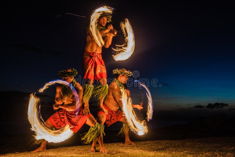 Bailarines hawaianos del fuego en el océano