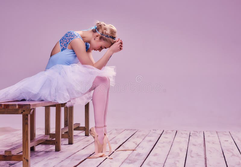 Bailarín de ballet cansado que se sienta en el piso de madera fotografía de archivo libre de regalías Bailarín de ballet cansado que se sienta en el piso de madera fotografía de archivo libre de regalías