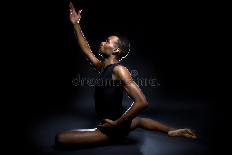 Black male dancer practicing warm up exercises for flexibility. Black male dancer practicing warm up exercises for flexibility