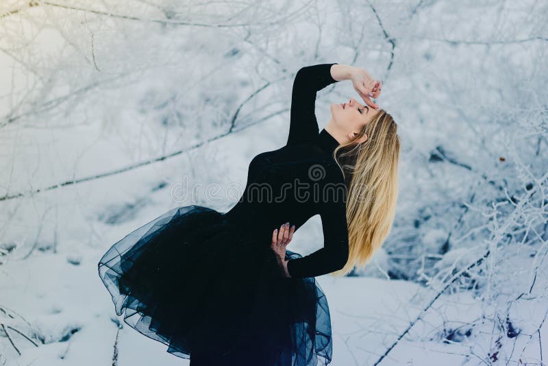 Bailarín en vestido negro en el bosque de la nieve foto de archivo Bailarín en vestido negro en el bosque de la nieve foto de archivo