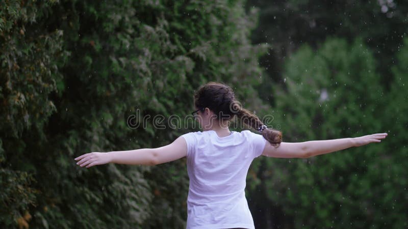 Baile de lluvia alegre : feliz muchacha celebrando en cámara lenta