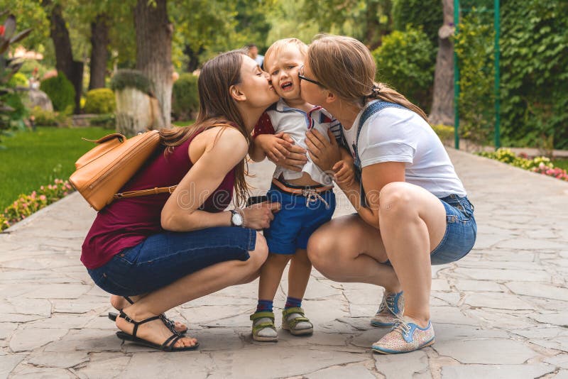 Baiser de maman de deux filles leur enfant capricieux de petit gar?on en parc Pas une famille traditionnelle photographie stock libre de droits Baiser de maman de deux filles leur enfant capricieux de petit gar?on en parc Pas une famille traditionnelle photographie stock libre de droits