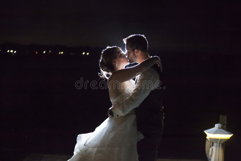 Baisers rétro-éclairés de couples de mariage de nuit photos stock