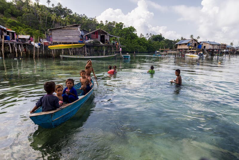 Bajau-Kinder entspannen sich auf einem gegrabenen heraus Boot nahe Küstenlinie in Sabah, Malaysia