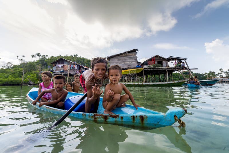 Bajau-Kinder entspannen sich auf einem gegrabenen heraus Boot nahe Küstenlinie in Sabah, Malaysia