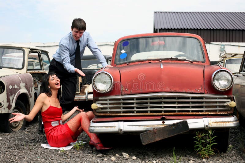 Girl and man beside retro car- under constructions to wheel. Girl and man beside retro car- under constructions to wheel