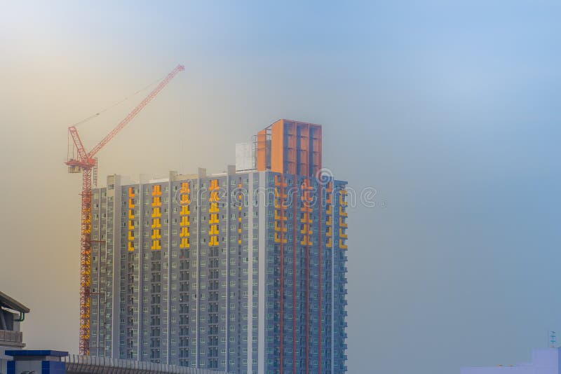 Bajo construcción del alto edificio de la subida del condominio con el fondo de grúa y del cielo azul foto de archivo libre de regalías Bajo construcción del alto edificio de la subida del condominio con el fondo de grúa y del cielo azul foto de archivo libre de regalías