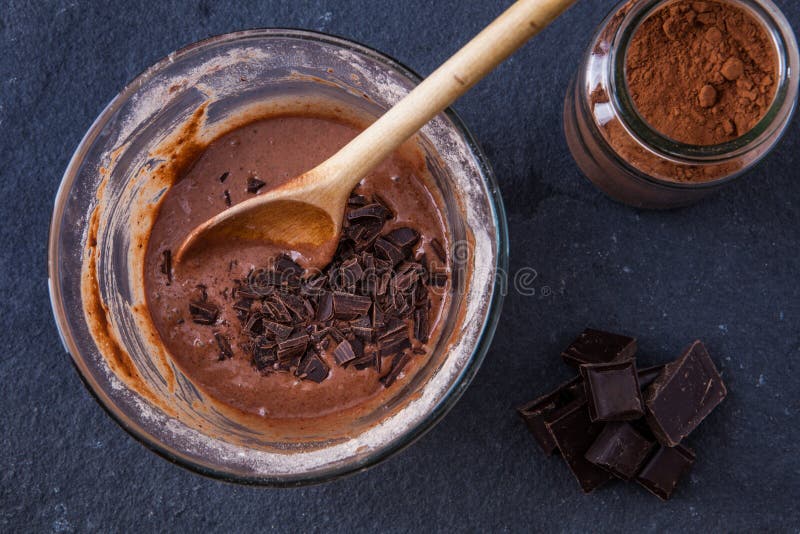 Baking a chocolate cake in a mug - mixing the dough with chocolate chips and cocoa powder on a slate background. Baking a chocolate cake in a mug - mixing the dough with chocolate chips and cocoa powder on a slate background