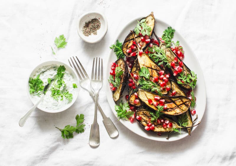 Bakad aubergine med feta, grekisk yoghurt, koriandersås och granatäpplefrö på ljus bakgrund, bästa sikt Läckert mellanmål, tapas royaltyfria bilder Bakad aubergine med feta, grekisk yoghurt, koriandersås och granatäpplefrö på ljus bakgrund, bästa sikt Läckert mellanmål, tapas royaltyfria bilder