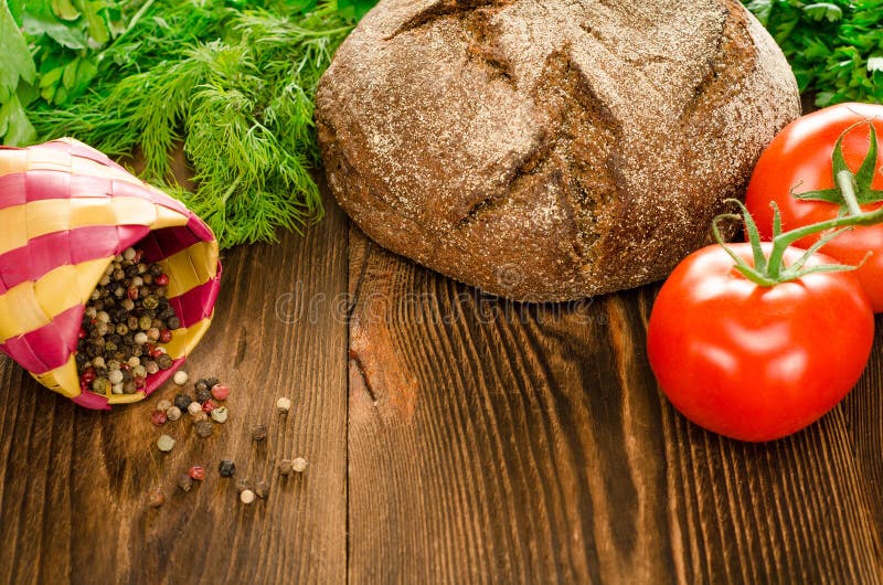 Bakat bröd med tomater, gräsplaner och peppar på bakgrund arkivbilder Bakat bröd med tomater, gräsplaner och peppar på bakgrund arkivbilder