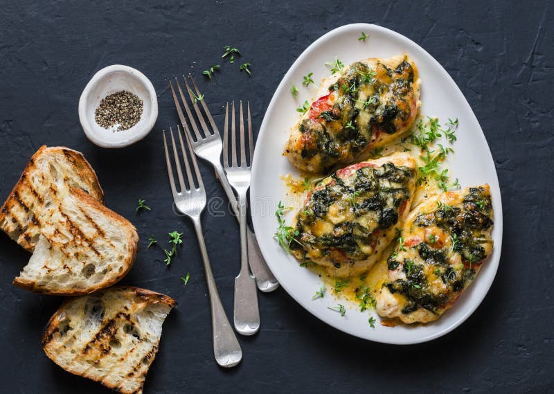 Bakat fegt bröst med den läckra tomater, spenat och mozzarellaen - banta lunch i medelhavs- stil på en mörk bakgrund royaltyfria foton Bakat fegt bröst med den läckra tomater, spenat och mozzarellaen - banta lunch i medelhavs- stil på en mörk bakgrund royaltyfria foton