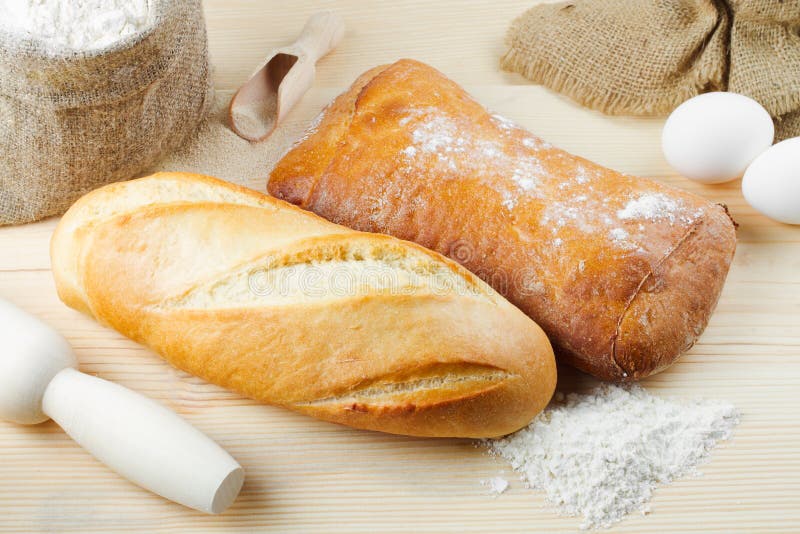 Baked baguette and bread on wooden board