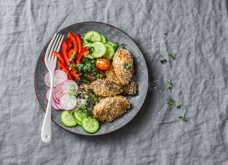 Baked chicken breast with sesame and fresh vegetables salad - healthy diet lunch on grey background stock photos Baked chicken breast with sesame and fresh vegetables salad - healthy diet lunch on grey background stock photos