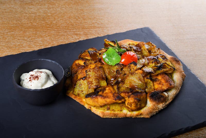 Baked chicken tights and breast served on a pita bread or focaccia pizza dough, restaurant setting