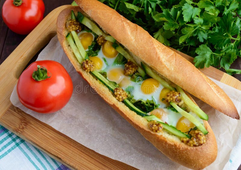 Baked crispy baguette with fried eggs, cucumbers stock photo