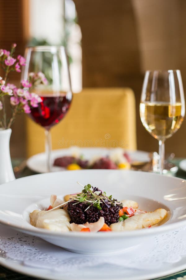 Baked Fish and Black Rice. Dinner with Wine Stock Photo - Image of