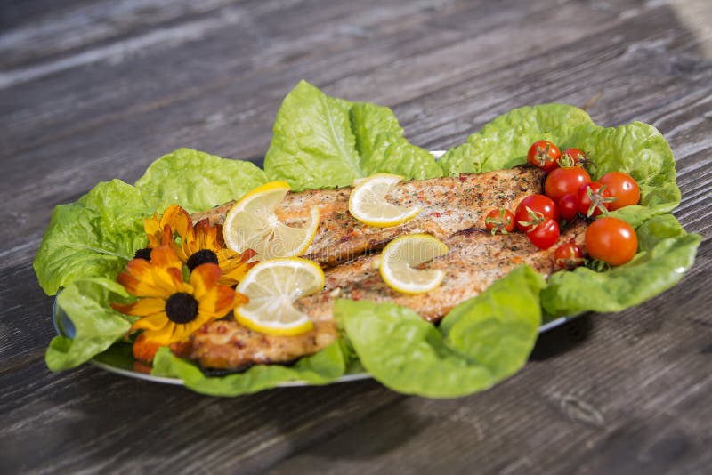 Baked fish slices with tomato and salad