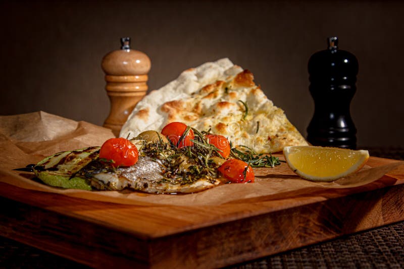 Baked Fish with Tomatoes, Zucchini and Rosemary on Paper Stock Image