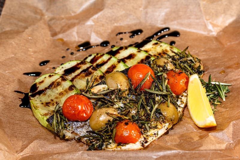 Baked Fish with Tomatoes, Zucchini and Rosemary on Paper Stock Image