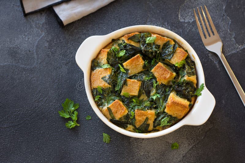 Baked Green Omelet with Spinach and Croutons, in White Form on Dark Textured Background Stock
