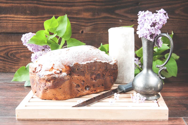 Baked homemade cake dusted with powder stands on a white plate near the lilac flowers stock images Baked homemade cake dusted with powder stands on a white plate near the lilac flowers stock images